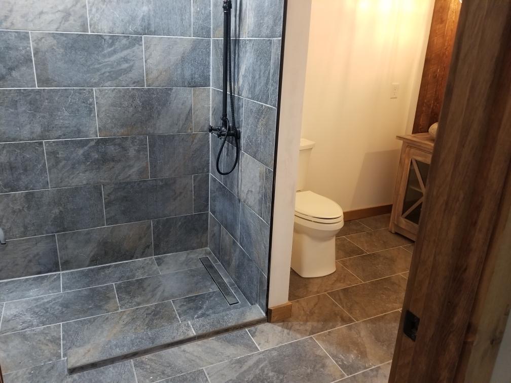 photo of Shower floor flows into shower with no threshold to step over. Linear drain in the floor blends in with the tile